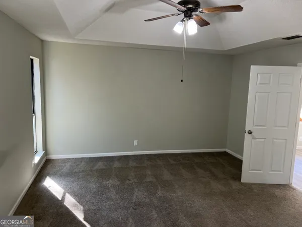 an empty room with a ceiling fan and a window