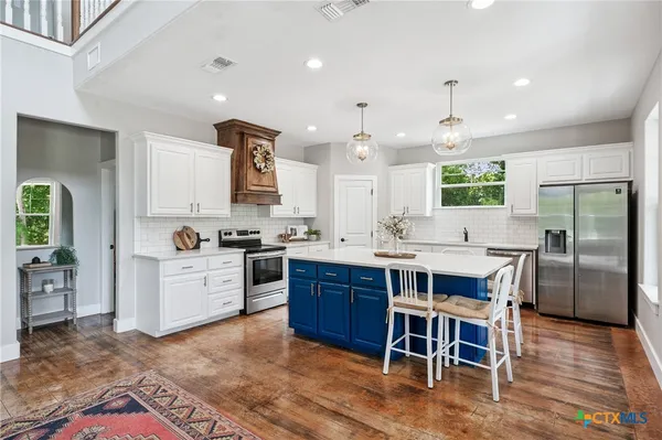 a kitchen with stainless steel appliances kitchen island granite countertop a table chairs sink and cabinets