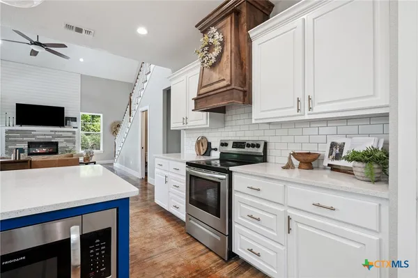 a kitchen with stainless steel appliances white cabinets and a stove top oven