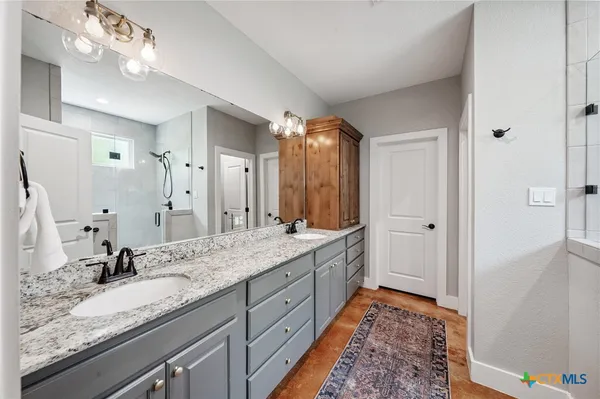 a bathroom with a granite countertop double vanity sink and a mirror