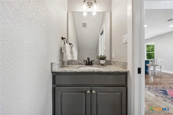 a bathroom with a granite countertop sink and a mirror