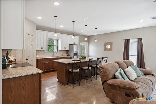 a living room with stainless steel appliances kitchen island granite countertop furniture a sink a counter top space and a center island