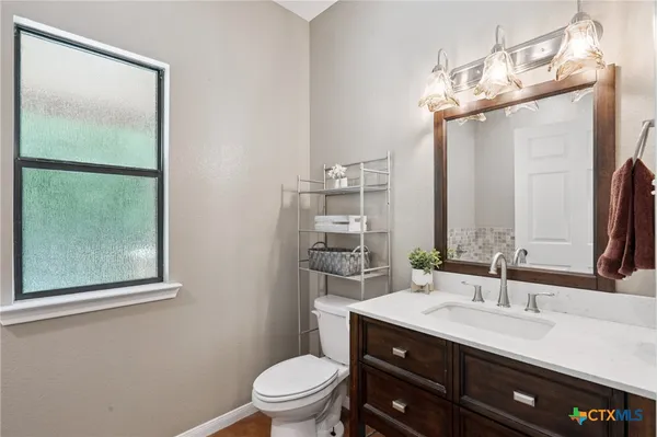a bathroom with a toilet a sink a vanity and mirror