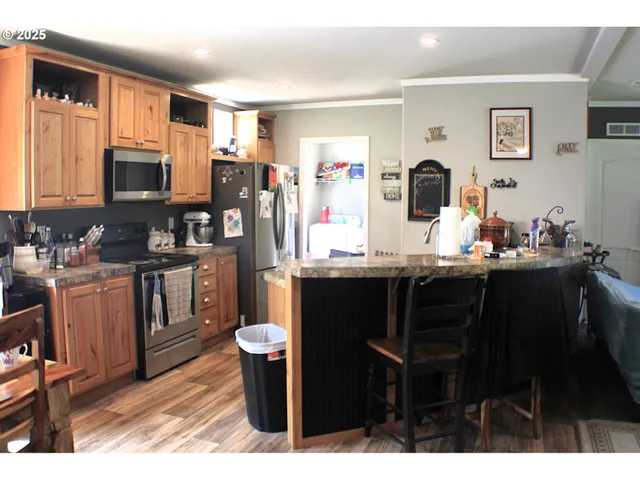 a kitchen with stainless steel appliances kitchen island granite countertop a table chairs and a refrigerator