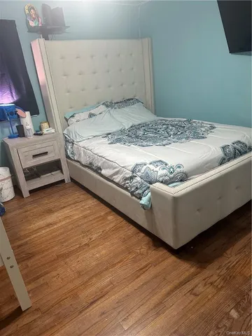 a bed sitting in a bedroom next to a window with wooden floor