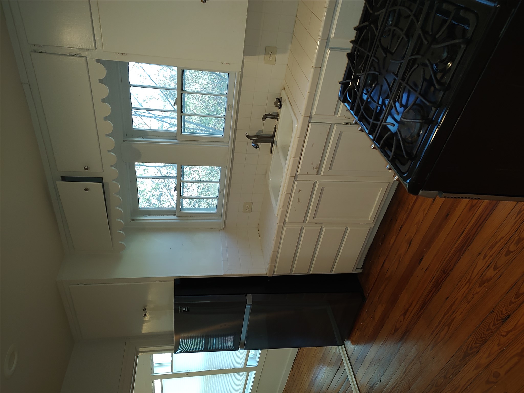 2102 Yellow Jacket Lane, Unit A Austin, TX 78741 - Photo 8 of 15 Kitchen featuring black appliances, white cabinets, tile counters, dark wood-type flooring, and decorative backsplash