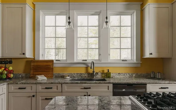 a kitchen with granite countertop a stove a sink and a white cabinets