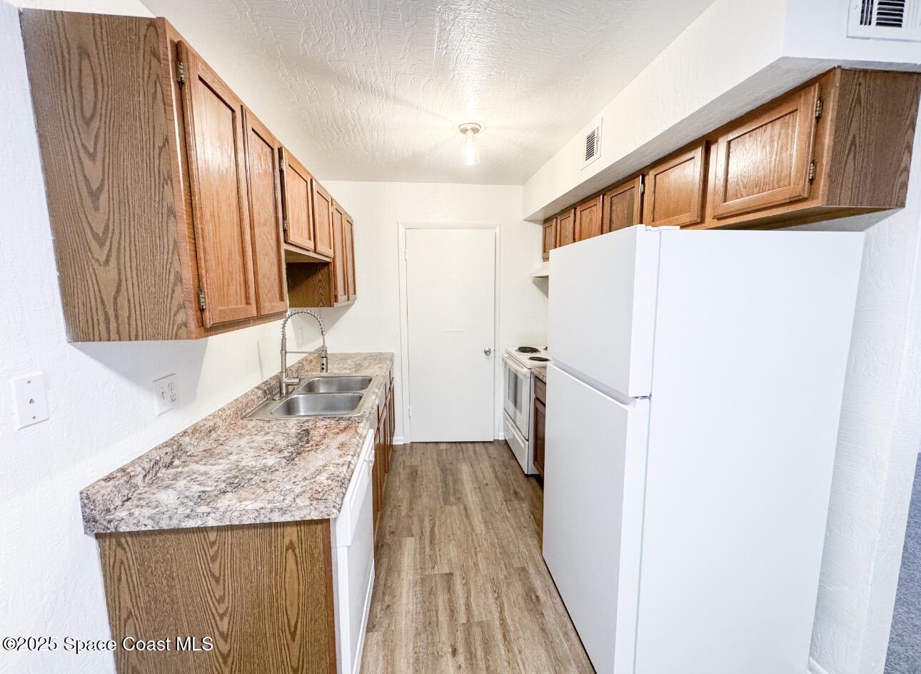 2130 Forest Knoll Drive Northeast, Unit 30208 Palm Bay, FL 32905 - Photo 7 of 19 a kitchen with granite countertop a refrigerator a sink and dishwasher