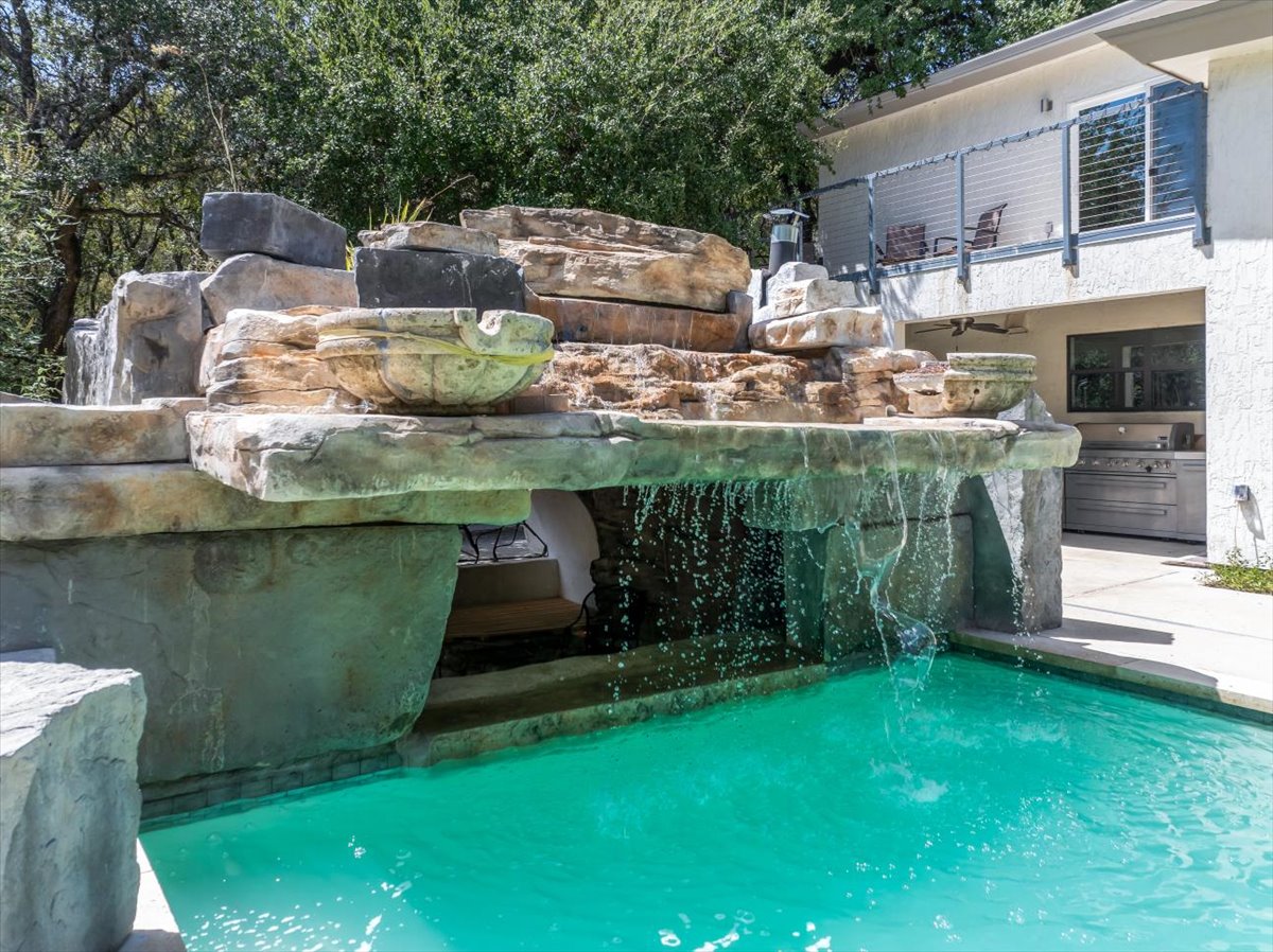 207 Rogers Ridge Street San Marcos, TX 78666 - Photo 27 of 35 A cascading natural-stone waterfall creates a resort-style focal point, revealing a secluded grotto tucked beneath for a private escape.