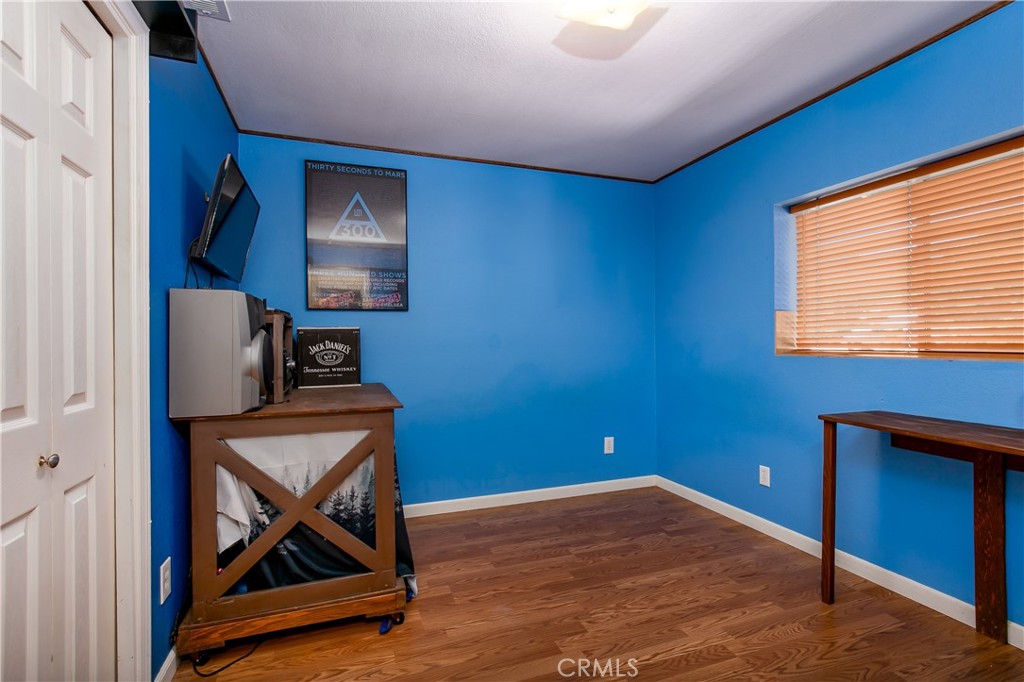10960 Steinhoff Road Frazier Park, CA 93225 - Photo 34 of 46 A spacious third bedroom located upstairs off the main hallway. This vibrant room showcases striking blue walls, continuous rich wood flooring, a decorative corner media console setup, and a wide window with wooden blinds that provides excellent natural light.