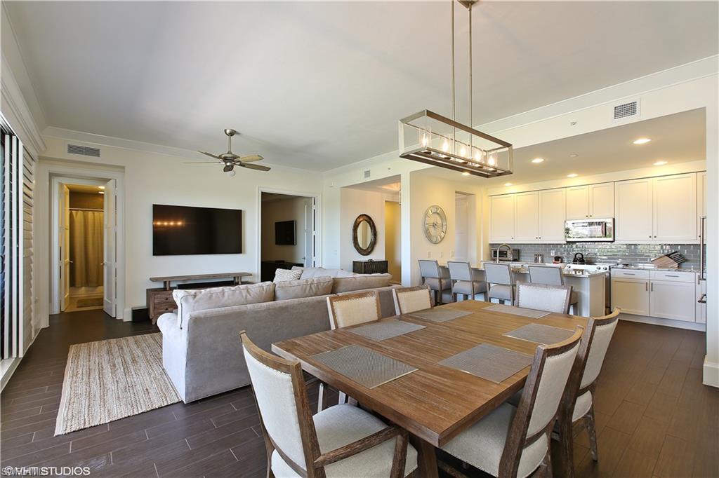 a living room with stainless steel appliances kitchen island a table and chairs in it