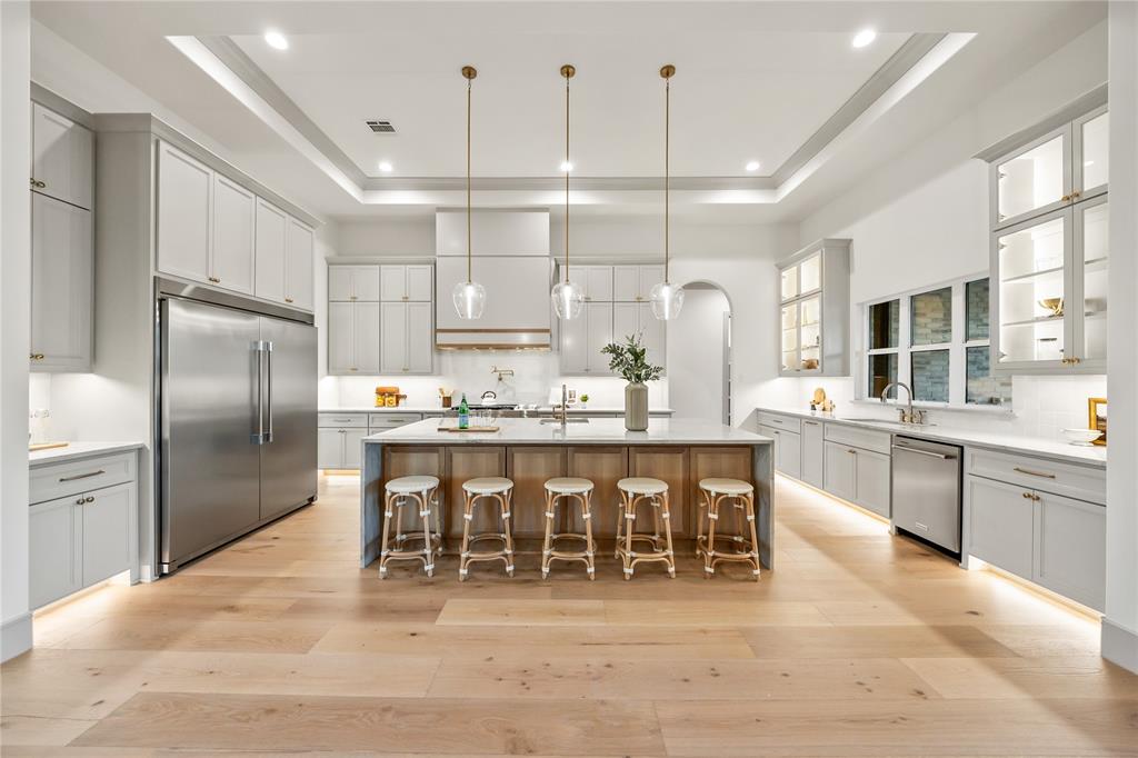 724 Cooper Trail Weatherford, TX 76087 - Photo 6 of 37 Spacious kitchen featuring light wood-finish flooring, a large center island with seating, extensive grey cabinetry, stainless steel appliances, and tray ceilings with recessed lighting