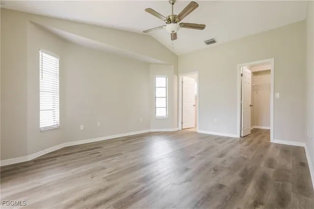 a view of an empty room with window and wooden floor