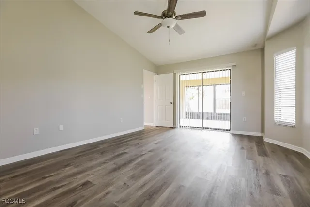 an empty room with wooden floor fan and windows