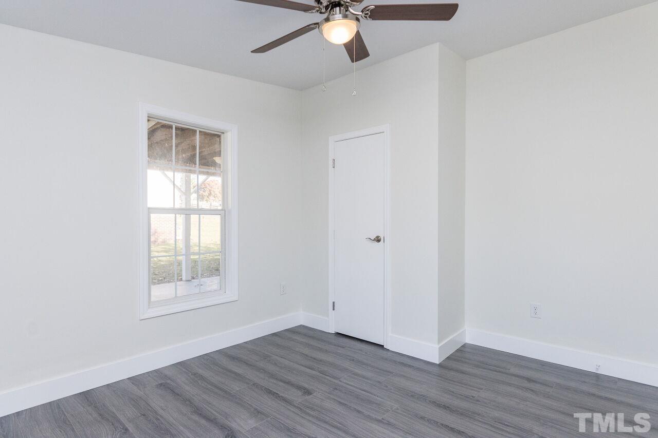 233 Eisler Drive Lillington, NC 27546 - Photo 17 of 29 an empty room with wooden floor chandelier fan and windows