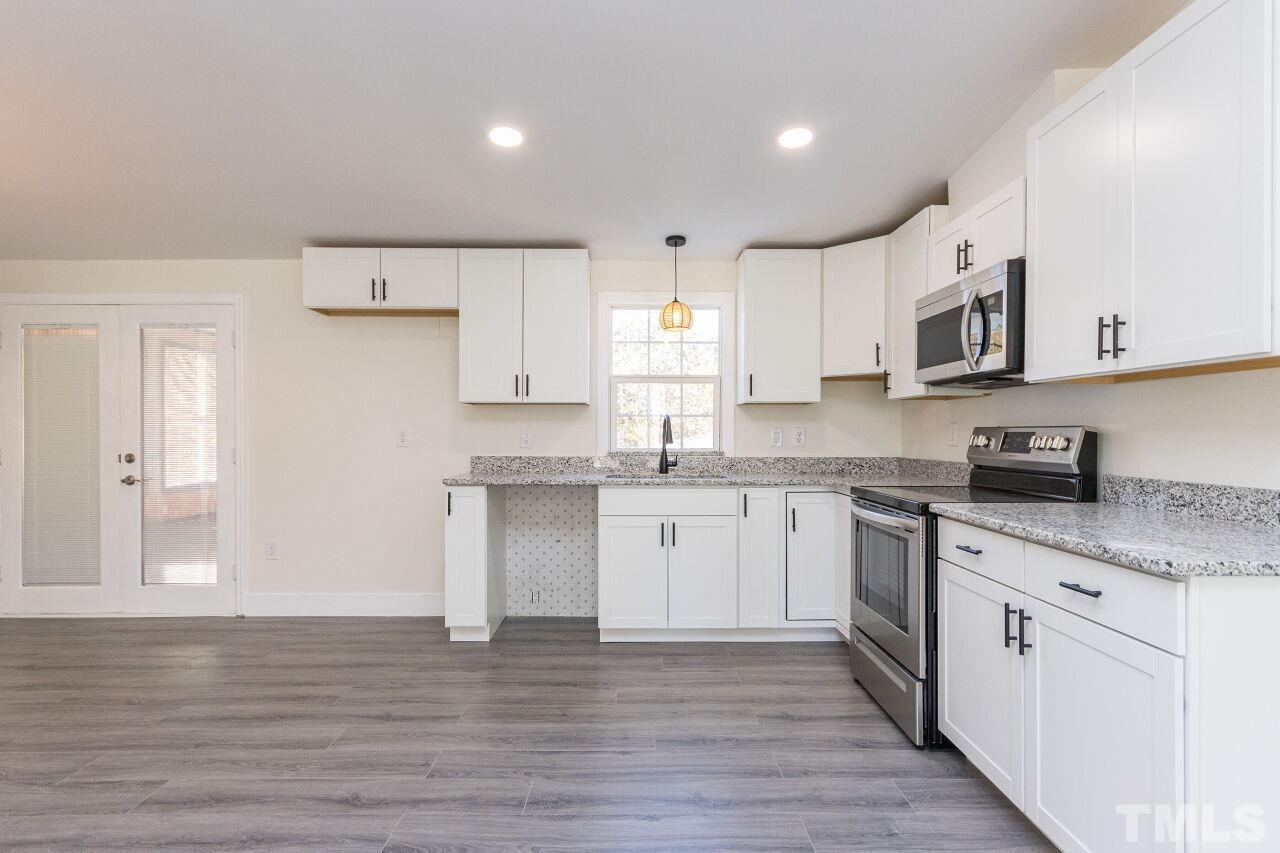 233 Eisler Drive Lillington, NC 27546 - Photo 9 of 29 a kitchen with granite countertop white cabinets and white appliances