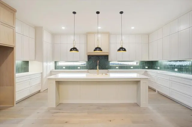 a view of a kitchen with kitchen island a sink stainless steel appliances and cabinets