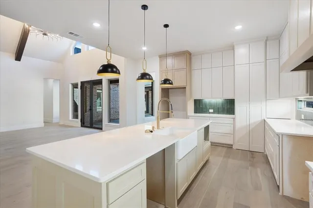 a large white kitchen with a large island oven a sink stainless steel appliances and cabinets