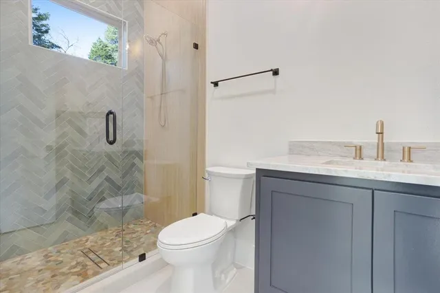a bathroom with a granite countertop sink a toilet and shower
