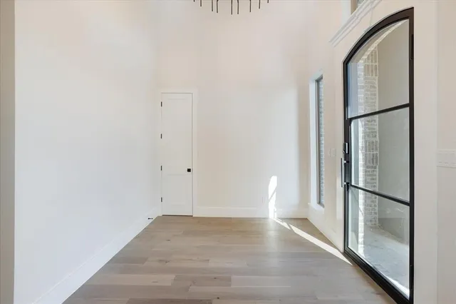 a view of empty room with wooden floor and a window