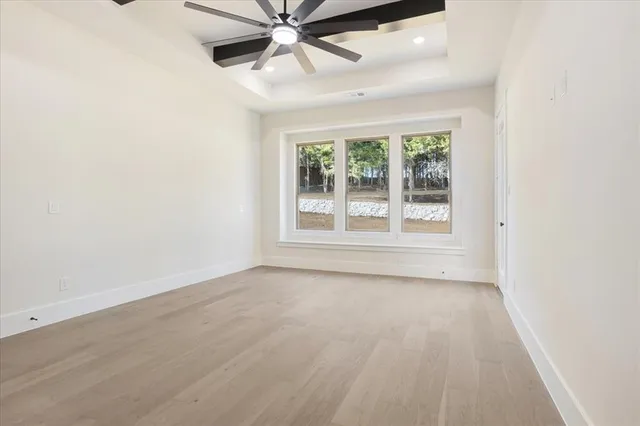 an empty room with wooden floor fan and windows