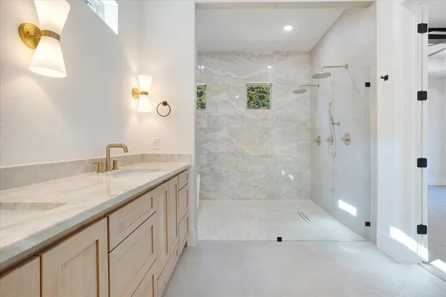 a bathroom with a granite countertop sink a mirror and a shower
