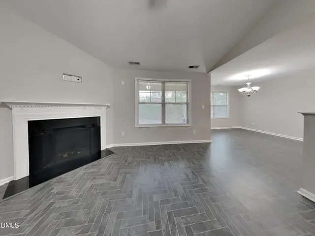 an empty room with windows and fireplace