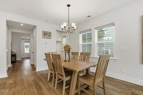 a dining room with wooden floor a chandelier a wooden table and chairs