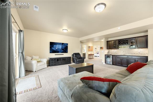 1131 Old North Gate Road Colorado Springs, CO 80921 - Photo 5 of 39 Living room featuring light carpet, wet bar, and wine cooler