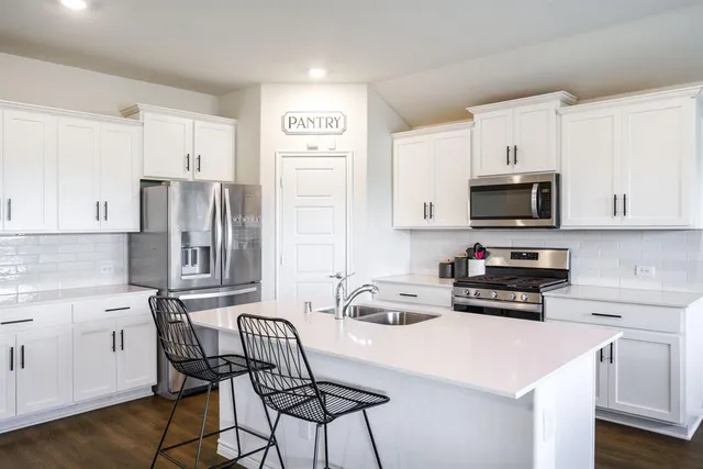 a kitchen with stainless steel appliances a stove a sink a stove a microwave and a refrigerator