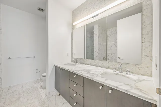 a bathroom with a granite countertop sink a toilet and shower