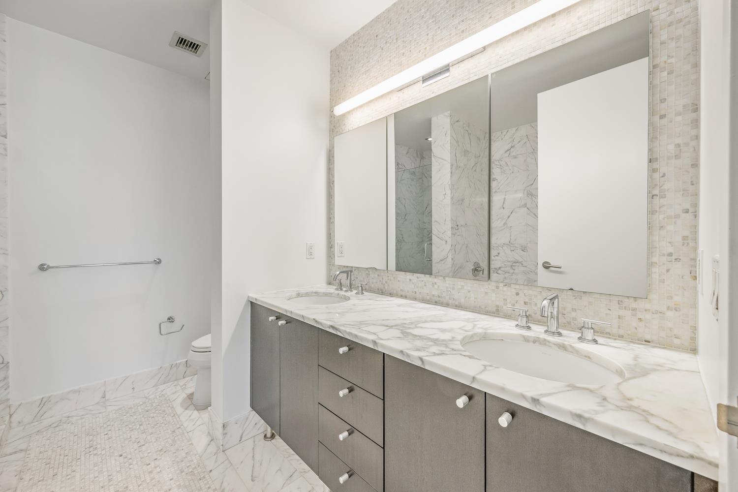 46-30 Center Boulevard, Unit 401 Queens, NY 11109 - Photo 6 of 18 a bathroom with a granite countertop sink toilet and mirror