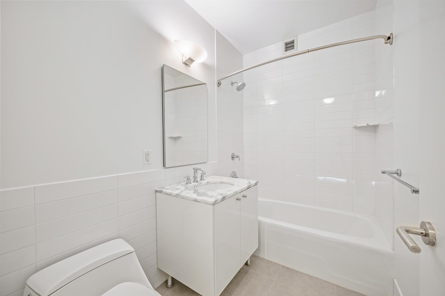 46-30 Center Boulevard, Unit 401 Queens, NY 11109 - Photo 7 of 18 a bathroom with a granite countertop sink a toilet and shower