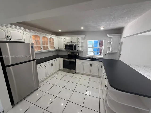 a kitchen with granite countertop a refrigerator sink and cabinets