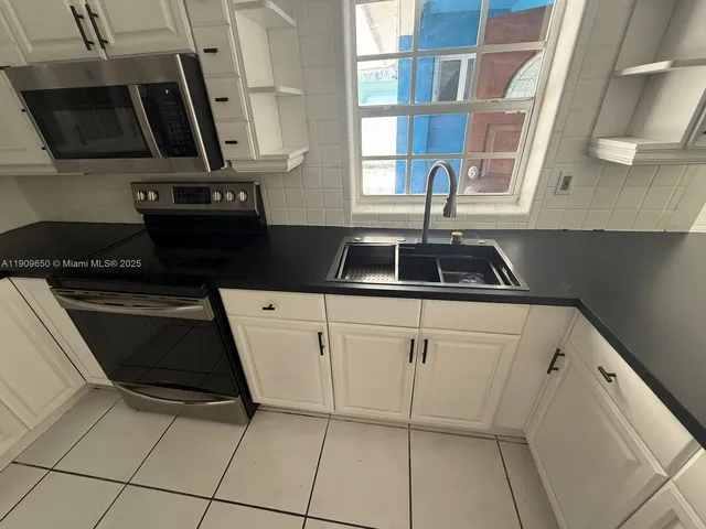 a large kitchen with granite countertop a sink and a stove top oven