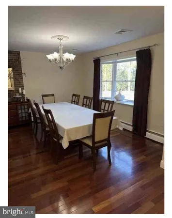 a dining room with wooden floor a chandelier a wooden table and chairs