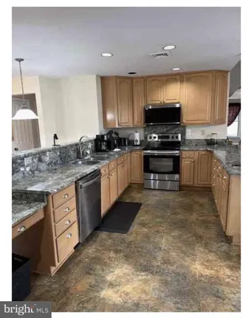 a large kitchen with stainless steel appliances granite countertop a stove sink and cabinets
