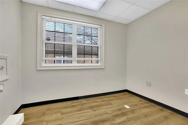 a view of an empty room with wooden floor and a window