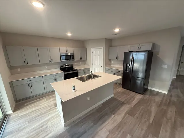 a large white kitchen with a refrigerator a sink dishwasher and a stove with wooden floor