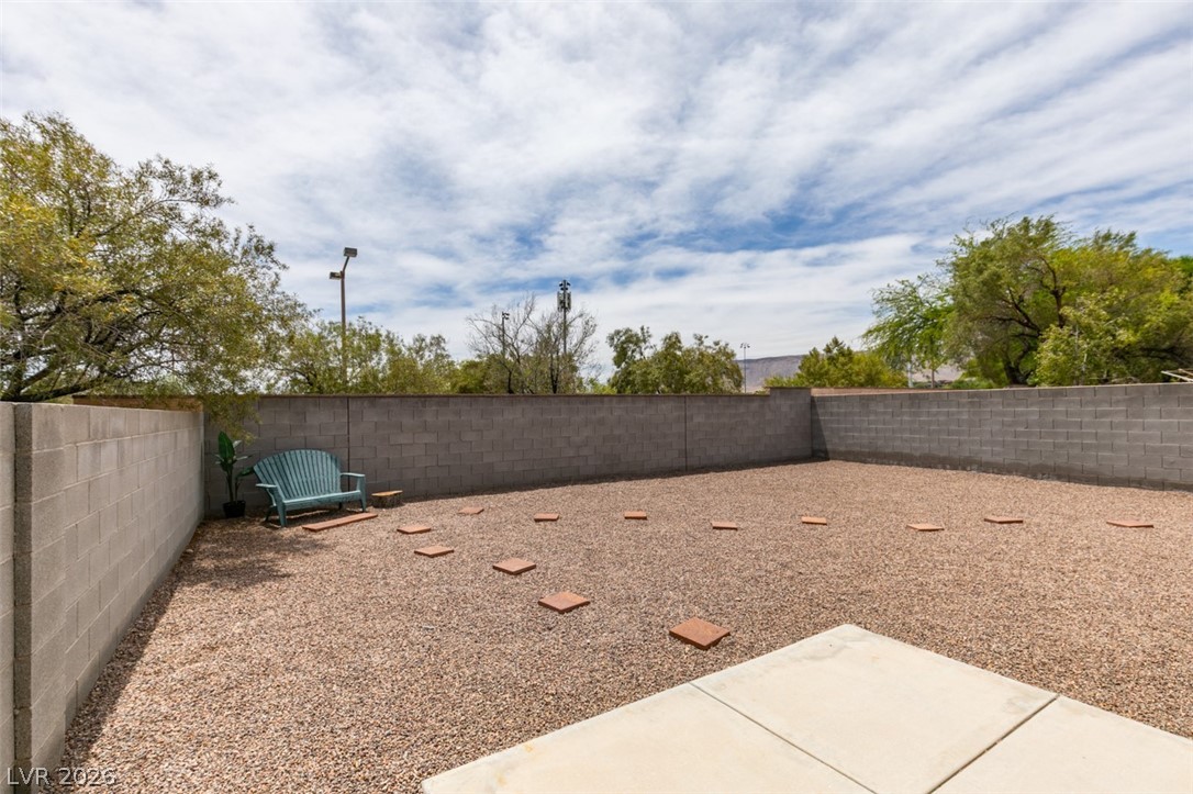 10959 Pumpkin Ridge Avenue Las Vegas, NV 89135 - Photo 30 of 51 A spacious gravel yard provides a versatile outdoor canvas, bordered by a privacy wall.