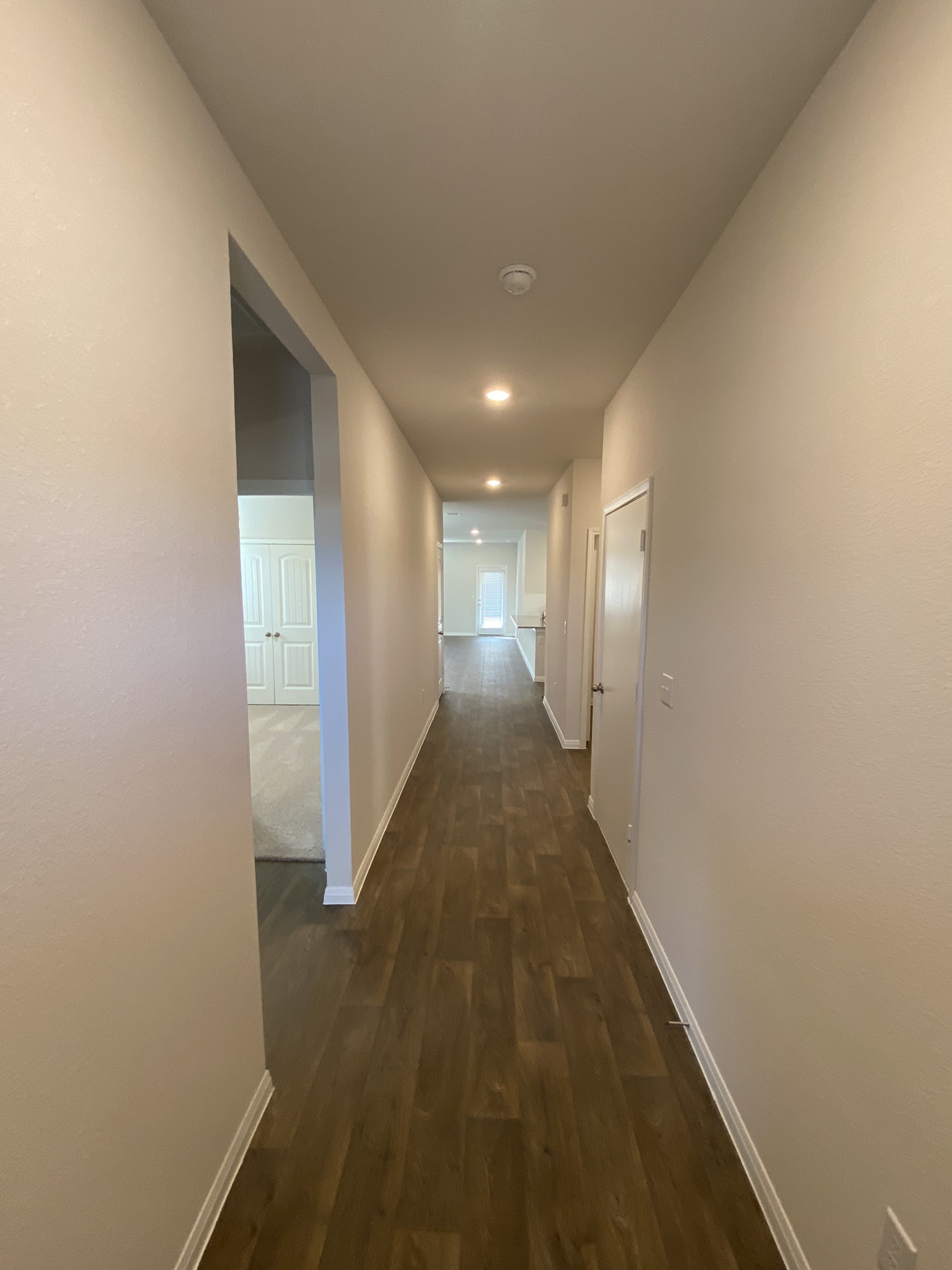 236 Sunniberg Loop Georgetown, TX 78626 - Photo 3 of 22 A long hallway lined with wood-style flooring and recessed lighting leads toward the living space.