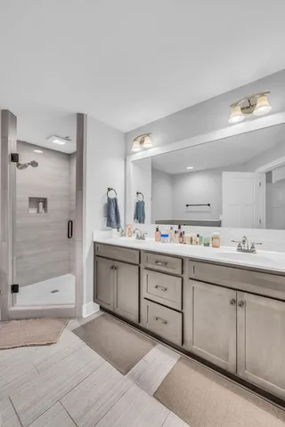 a spacious bathroom with a shower a sink and mirror