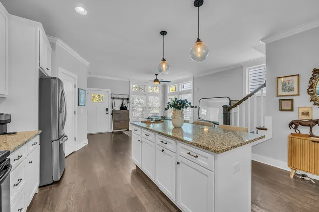 a kitchen with stainless steel appliances granite countertop cabinets a sink a refrigerator and a wooden floor