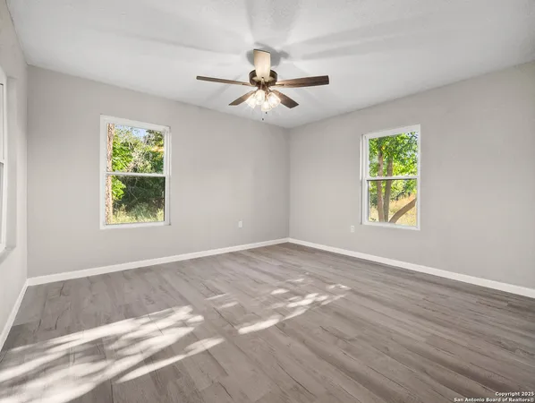 an empty room with windows and fan