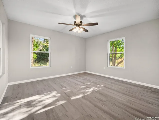 an empty room with windows and fan