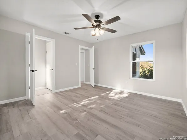 a view of an empty room with window and wooden floor