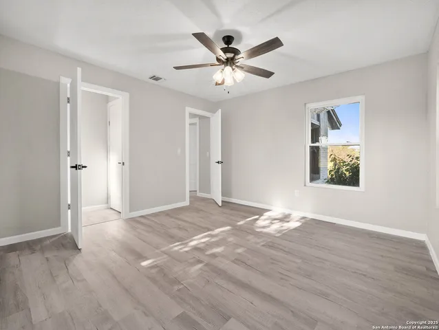 a view of an empty room with window and wooden floor