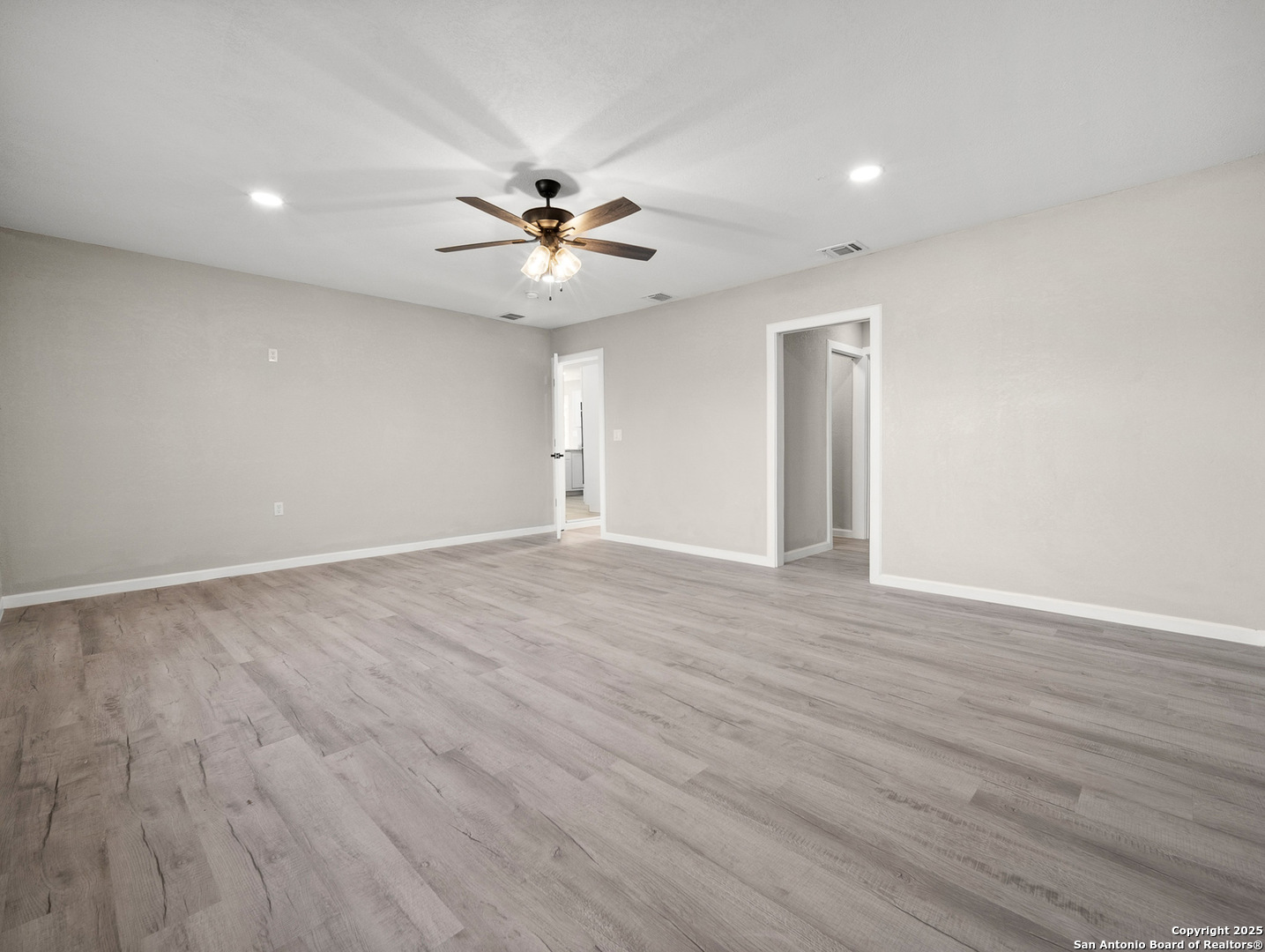 19551 Farm To Market Road 463 Devine, TX 78016 - Photo 19 of 27 a view of an empty room with wooden floor and a ceiling fan
