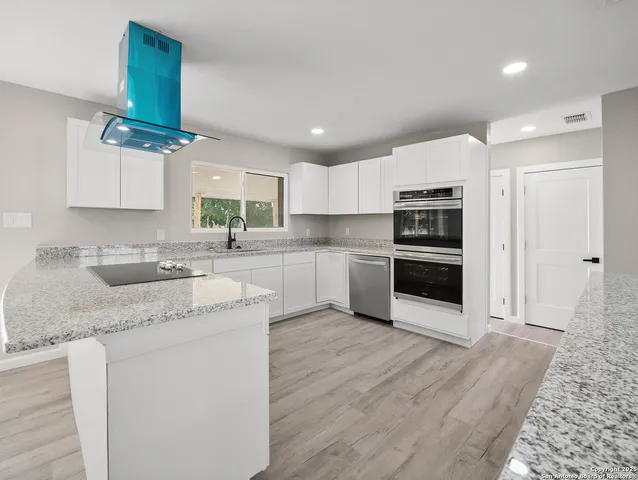 a kitchen with kitchen island granite countertop a sink cabinets and stainless steel appliances