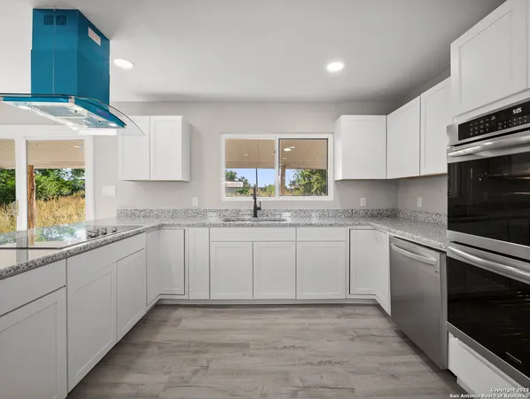 a kitchen with granite countertop a sink stainless steel appliances and cabinets